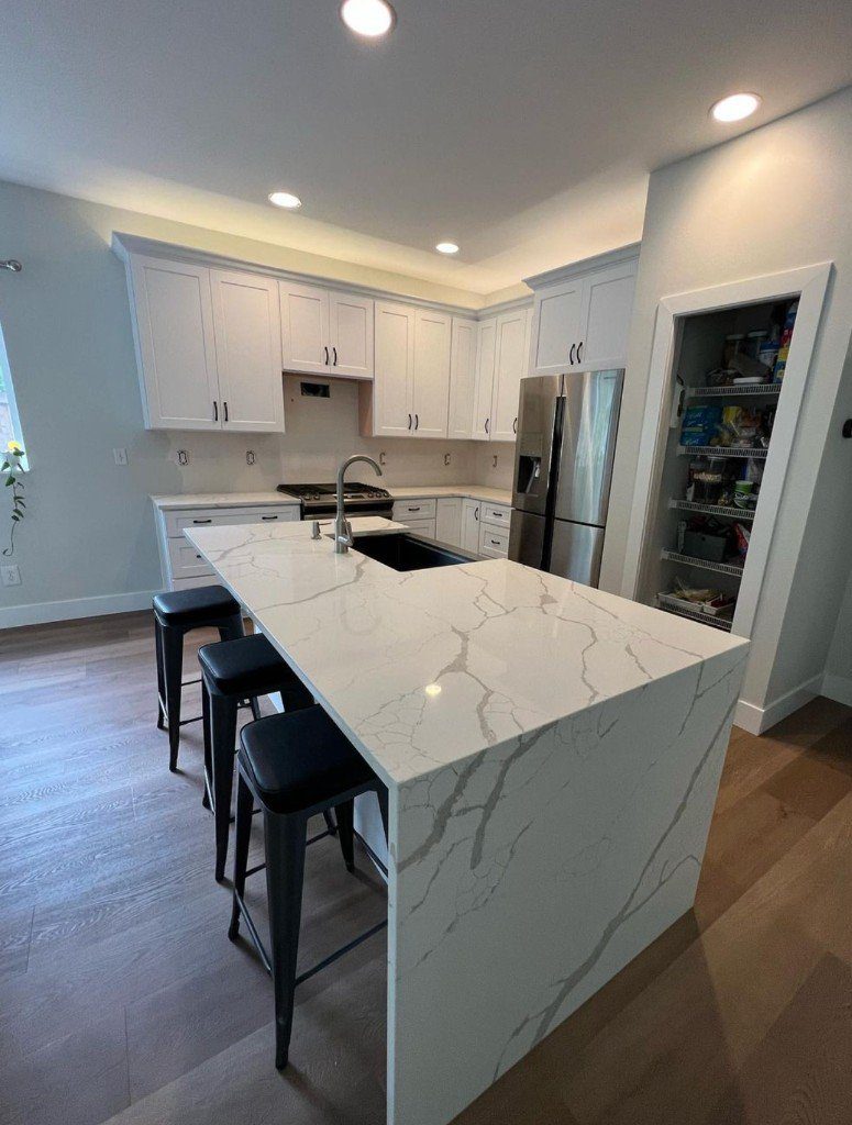 Completed Lion Heart kitchen with a quartz waterfall island and custom white cabinetry.