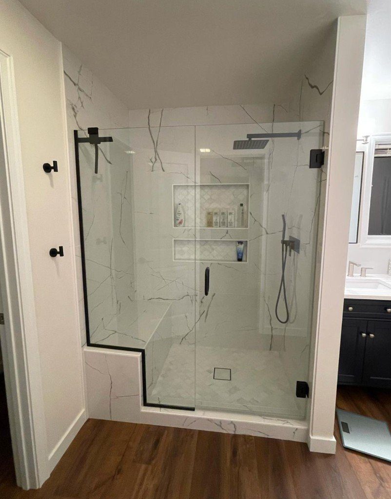 Completed Lion Heart walk-in shower with marble tile and black-framed glass