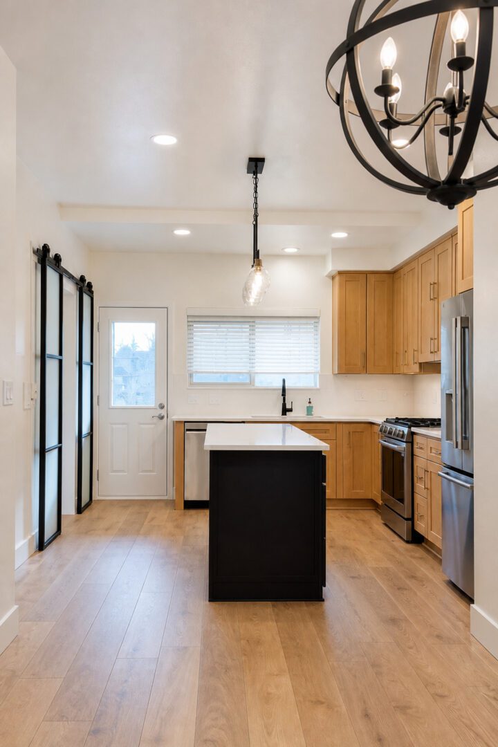 Completed Lion Heart kitchen with a black island, wood cabinets, and new floors.
